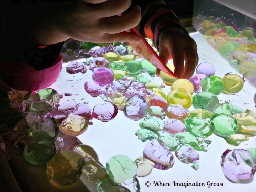 Light table activities for kids! Cutting and squishing water beads on the light table!