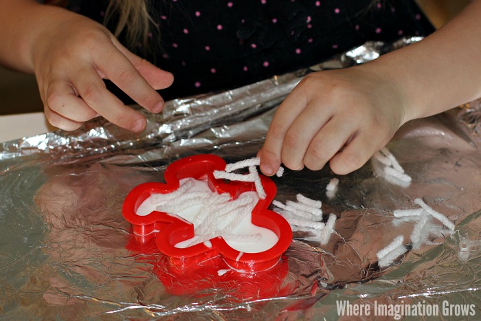 Halloween mummy craft for kids using yarn, glue, and mummy-shaped cookie cutters
