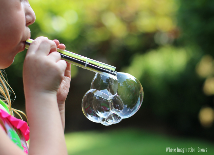 Child Blowing bubbles with DIY Straw Bubble Blower